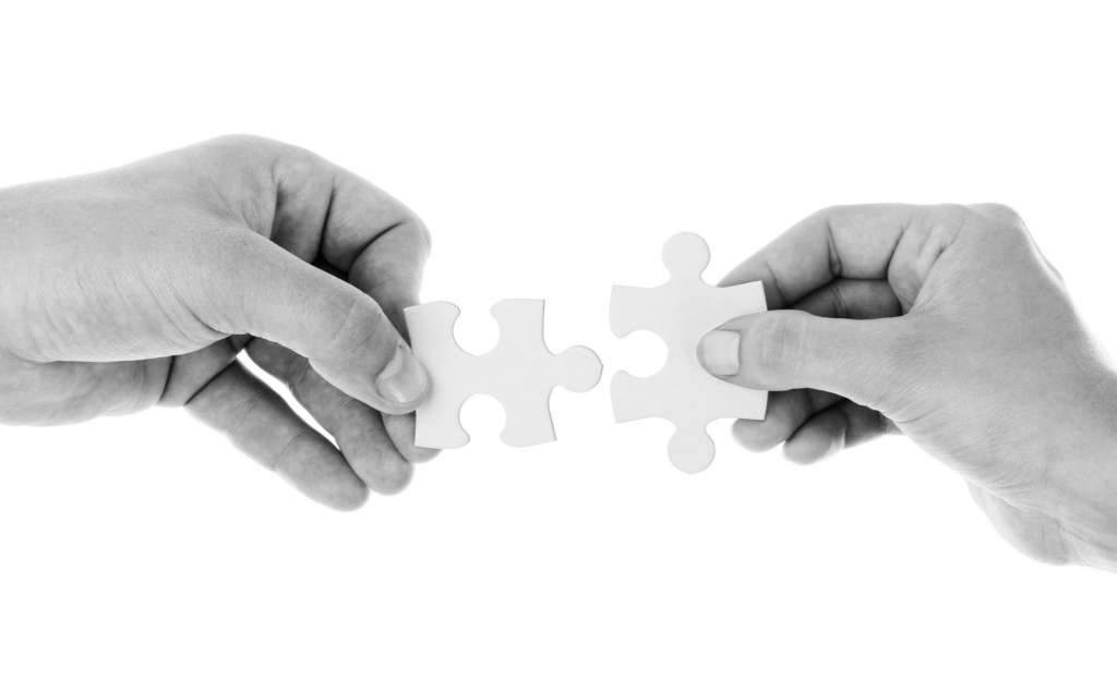 two hands arranging two puzzle pieces as a way of finding solution