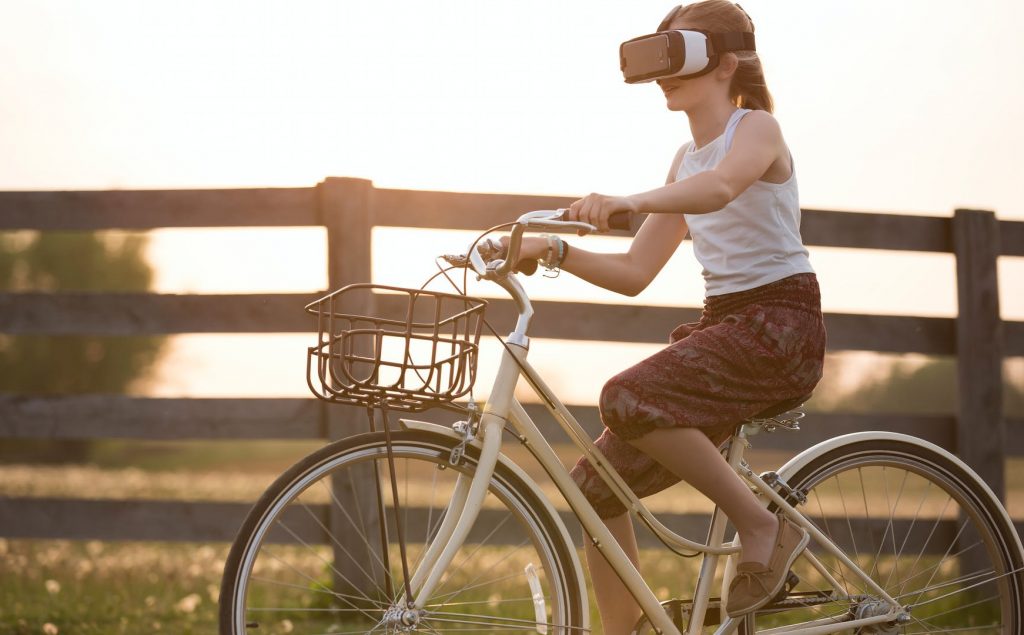 Girl riding a bike with a VR headset as a Media and Entertainment Industry Trend